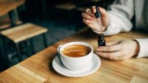 image showing a man making cbd coffee by dropping cbd into a cup of coffee